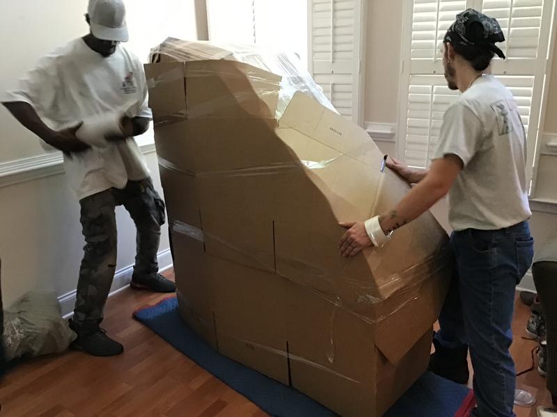 Liberty Pro crew building a cardboard protective shell around a tall furniture piece