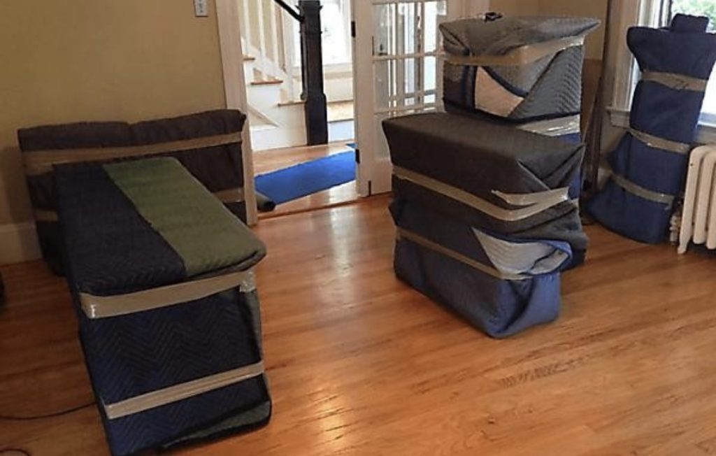 movers wrapping furniture with moving blankets